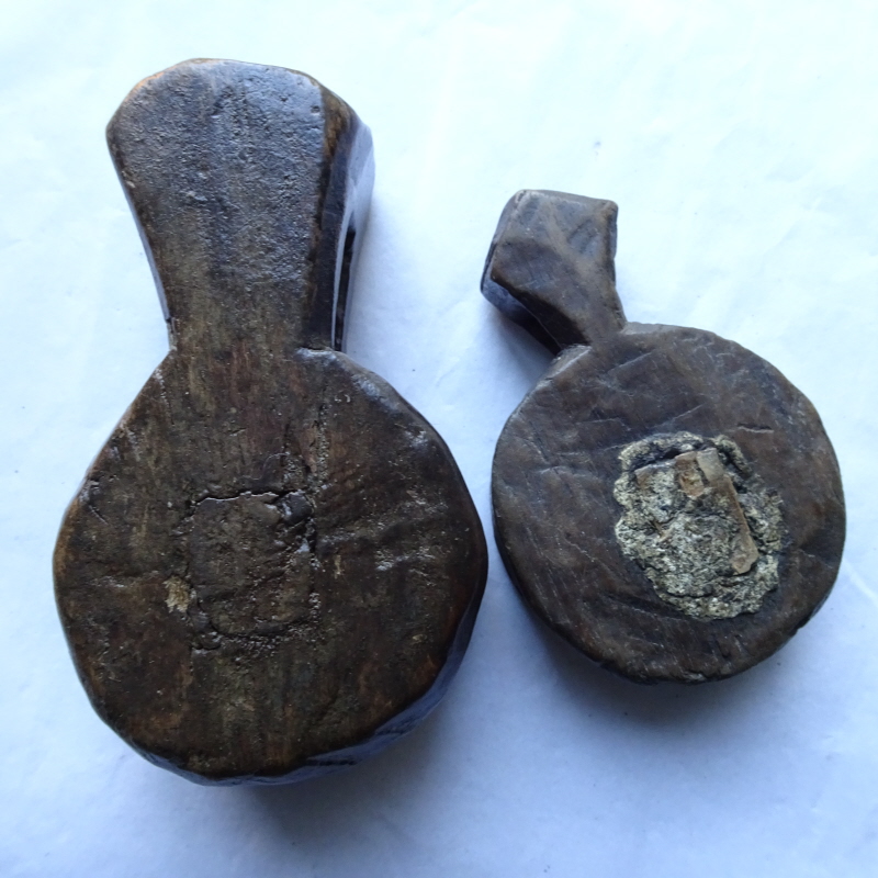 Two carved wooden amulets showing the places where holes were made, sacred items inserted and then resealed.
