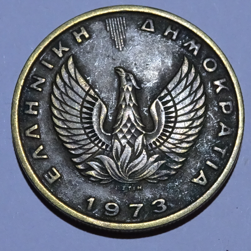 Greek coin with Phoenix rising from flames, sun rays above, and date, 1973.