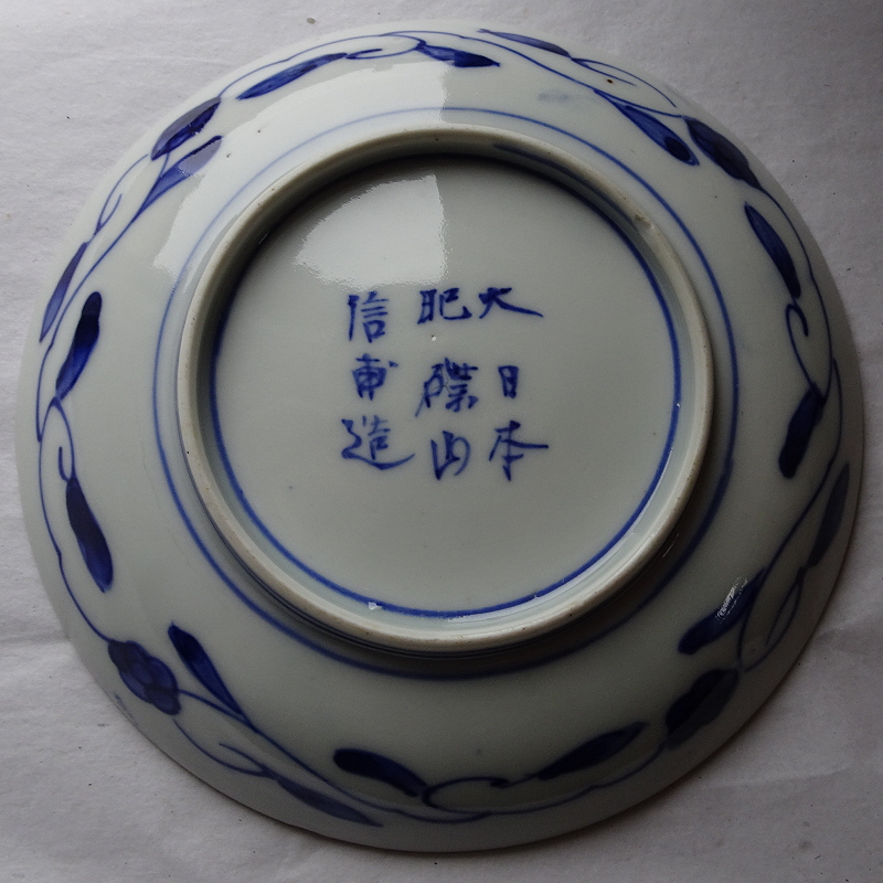 Reverse of the saucer showing Japanese text and blue leafy pattern.