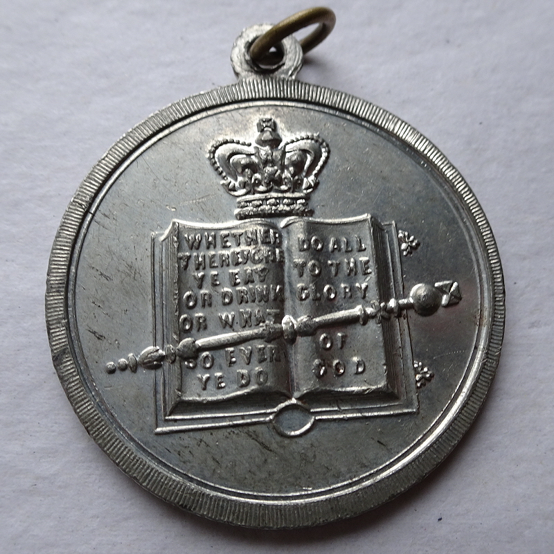 Church of England Temperance Society medal in nickel?????, showing a sceptre across an open book, with a crown at the top. The text on the book reads, "Whether therefore you eat or drink or what so ever ye do do all to the glory of God".