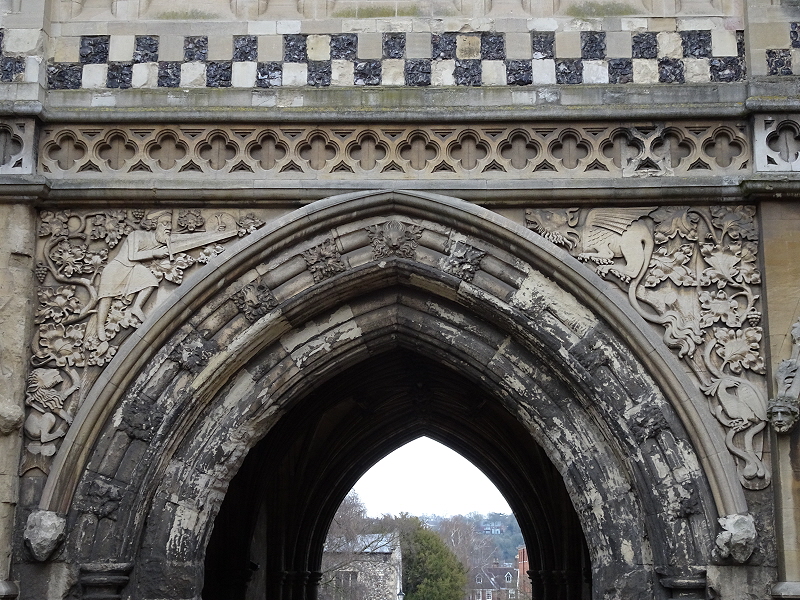 The Ethelbert Gate to Norwich Cathedral from Tombland, with a relief of a knight on the left, with sword and small shield, and dragon on the right, checkerboard pattern in flint above.